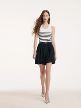 a lady in black bermuda shorts with  leather belt